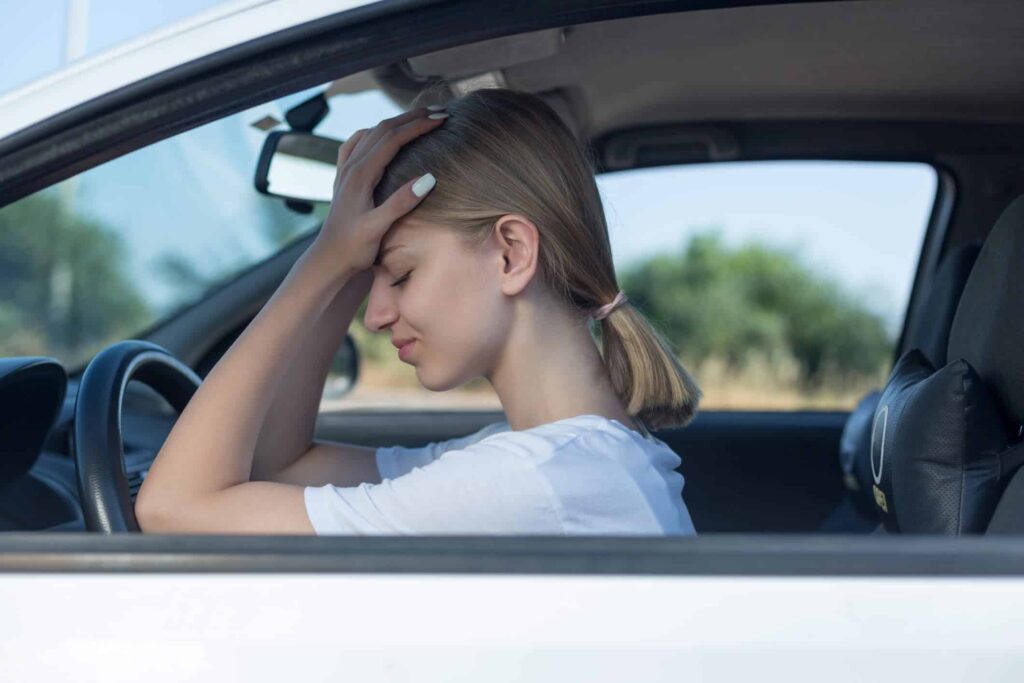 Saiba quais são os golpes mais comuns em carros novos e usados 7 Mulher dentro do carro com as duas mãos na cabeça - Vender carros com mais de 5 anos de uso