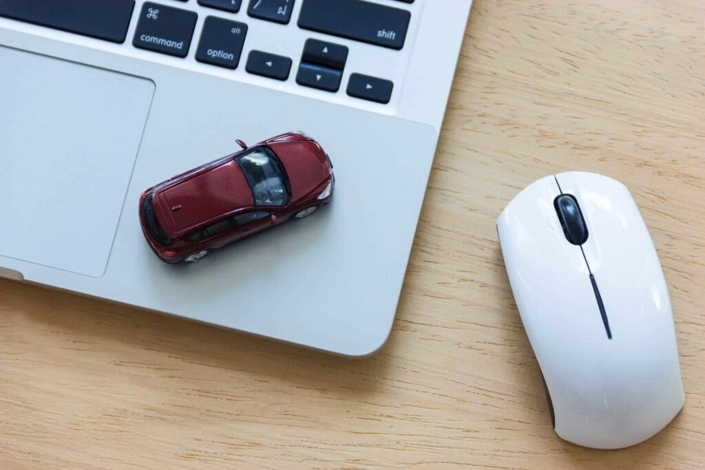 InstaCarro.com: venda de carros com eficiência e segurança! 7 mouse ao lado de um notebook com um carro de brinquedo em cima