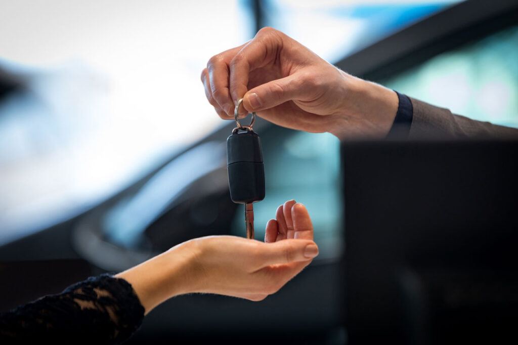 Como vender um carro alienado? 6 mão entregando uma chave de carro para outra mão - carro alienado