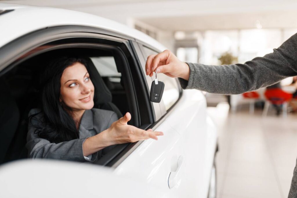 mulher feliz dentro do carro recendo a chave - carros até 30 mil