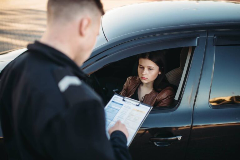 mulher triste dentro do carro recebendo uma multa de trânsito de um policial rodoviário mafia das multas