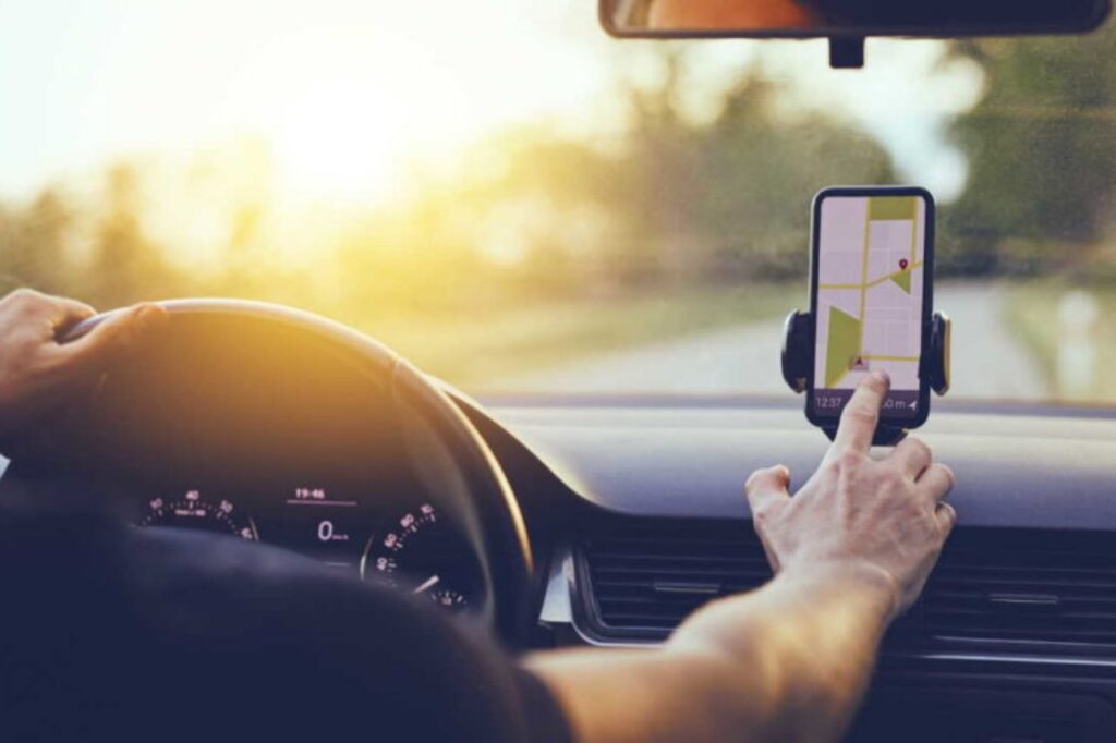 O que está acontecendo com os aplicativos de mobilidade? 1 aplicativos de mobilidade - mão masculina mexendo em celular dentro de carro
