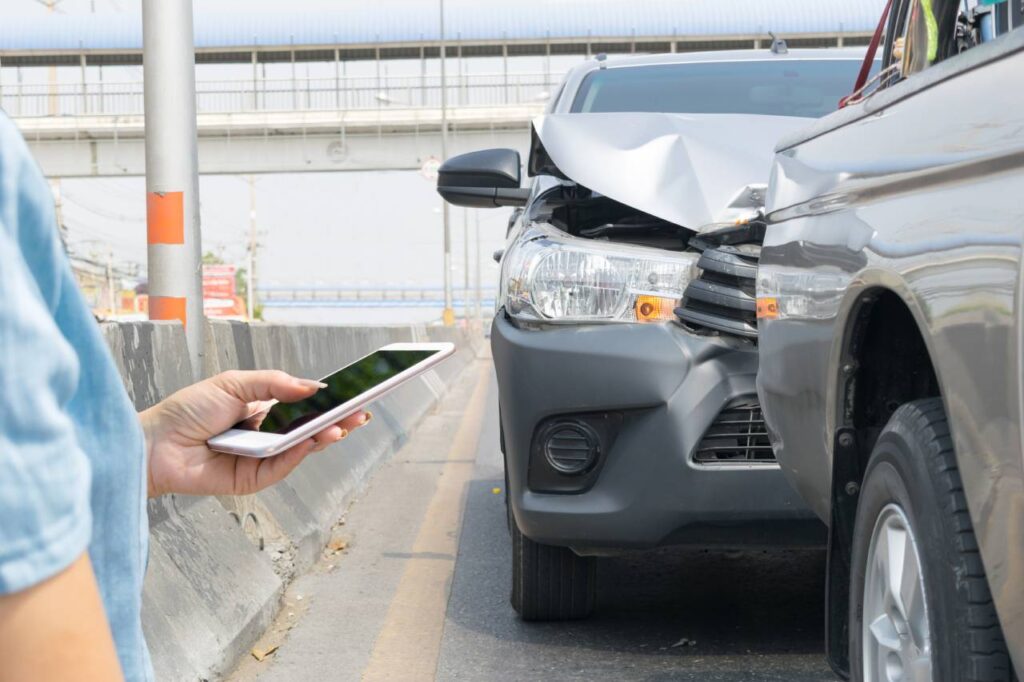 sinistros não cobertos pelo seguro - picape hilux batida atrás de outra picape e mulher segurando celular na mão