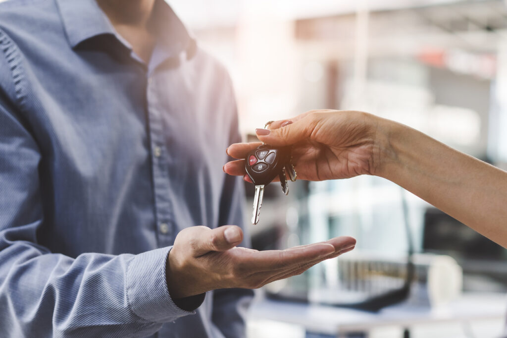 Como vender carro com histórico de leilão 3 vender carro em Duque de Caxias - mão de mulher entregando uma chave de carro na mão de um homem