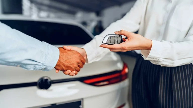 Blog 47 Imagem de um homem e uma mulher se cumprimentando com aperto de mãos e entregando uma chave canivete. Um carro branco ao fundo. vender carro pessoa física