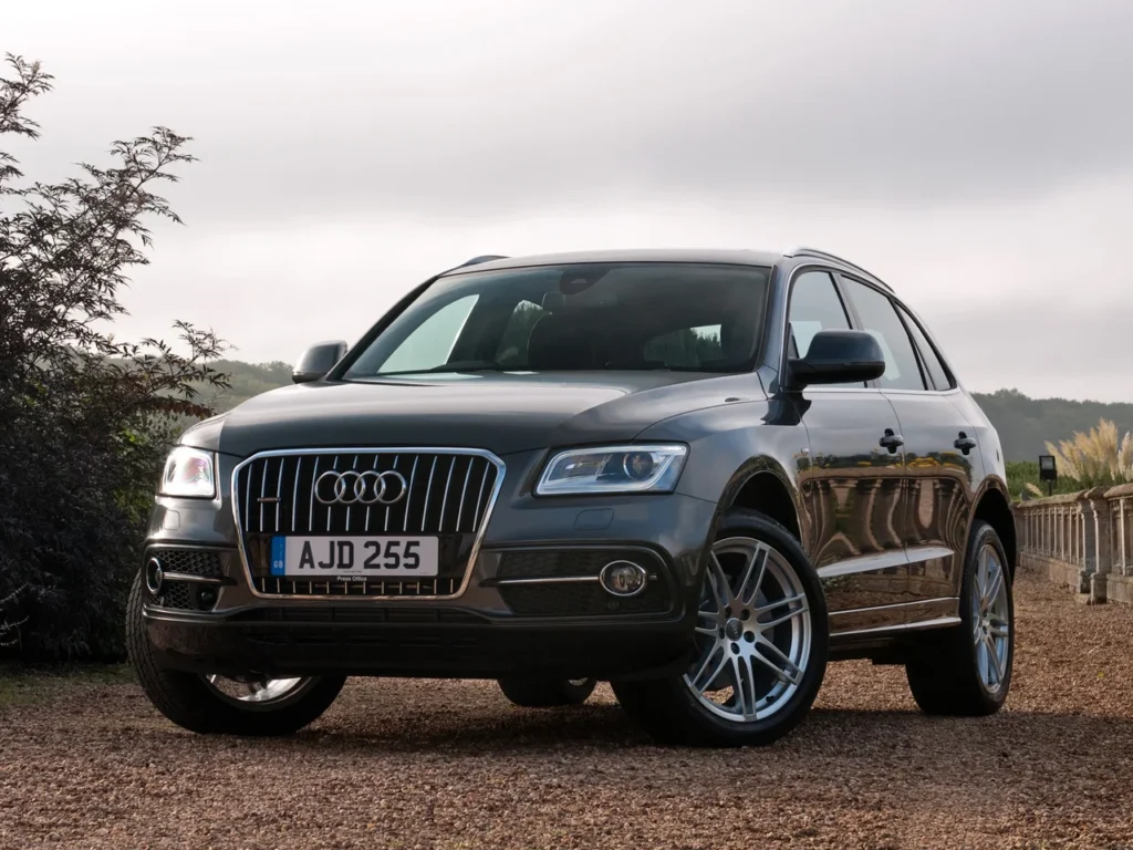 SUV Audi Q5 TDI Quattro S-Line cinza estacionado em estrada de terra com paisagem ao fundo.