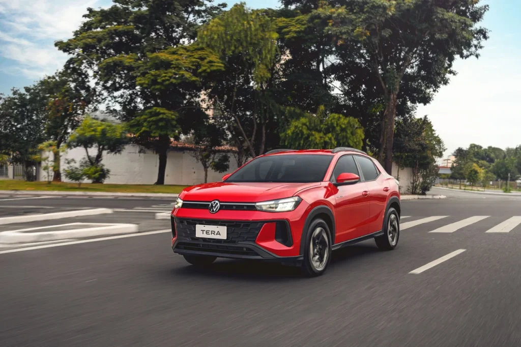VW Tera vermelho em movimento em uma avenida arborizada, destacando seu design esportivo e robusto.