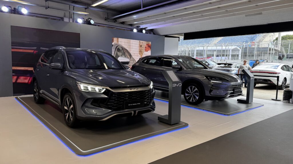Feira BYD com exposição de veículos elétricos e híbridos, incluindo os modelos BYD Song Pro e BYD Seal U, em estande iluminado com design moderno e informativo.