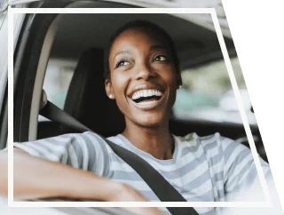Uma mulher dentro de um carro, sorrindo e com o braço apoiado na janela